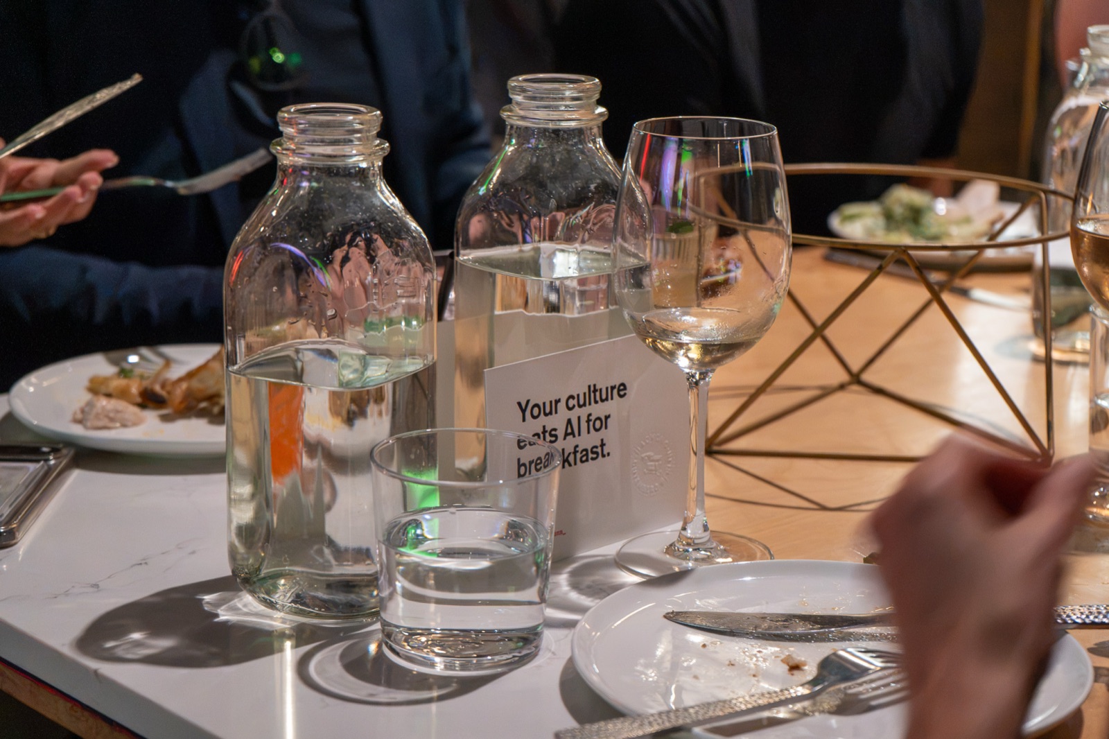 A table card reading Your culture eats AI for breakfast next to water bottles and glasses