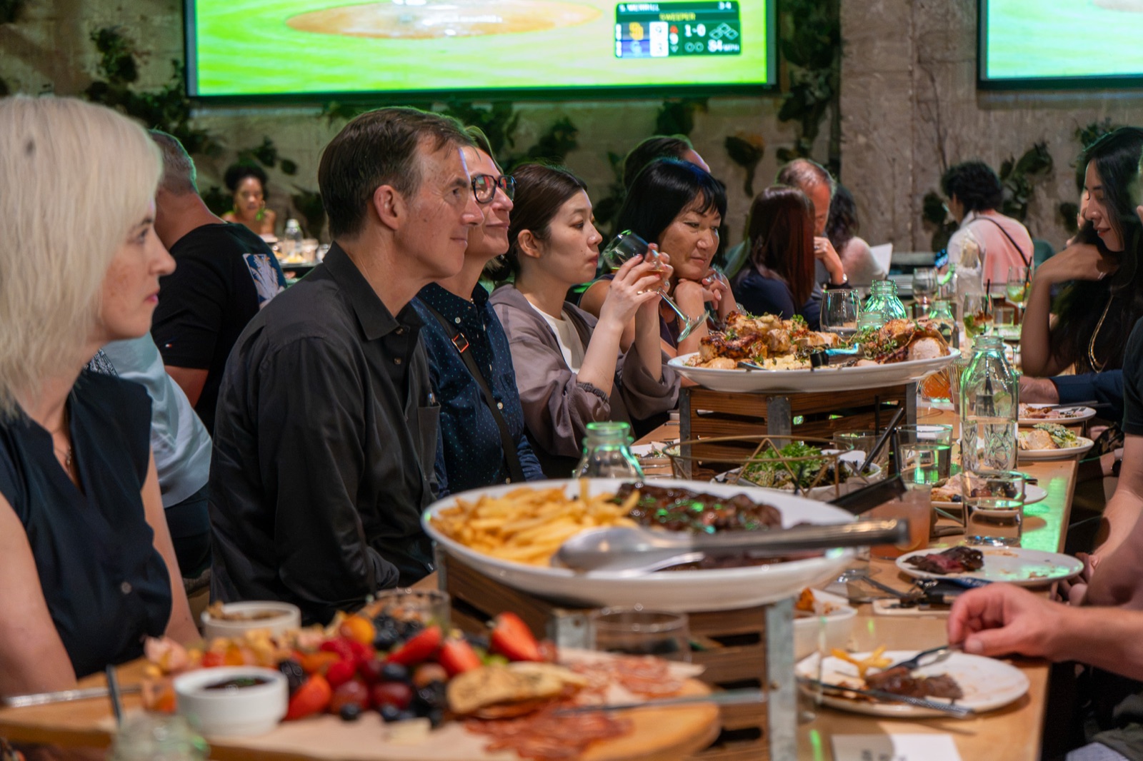 Guests listening along one side of the table with sharing platters in front of them