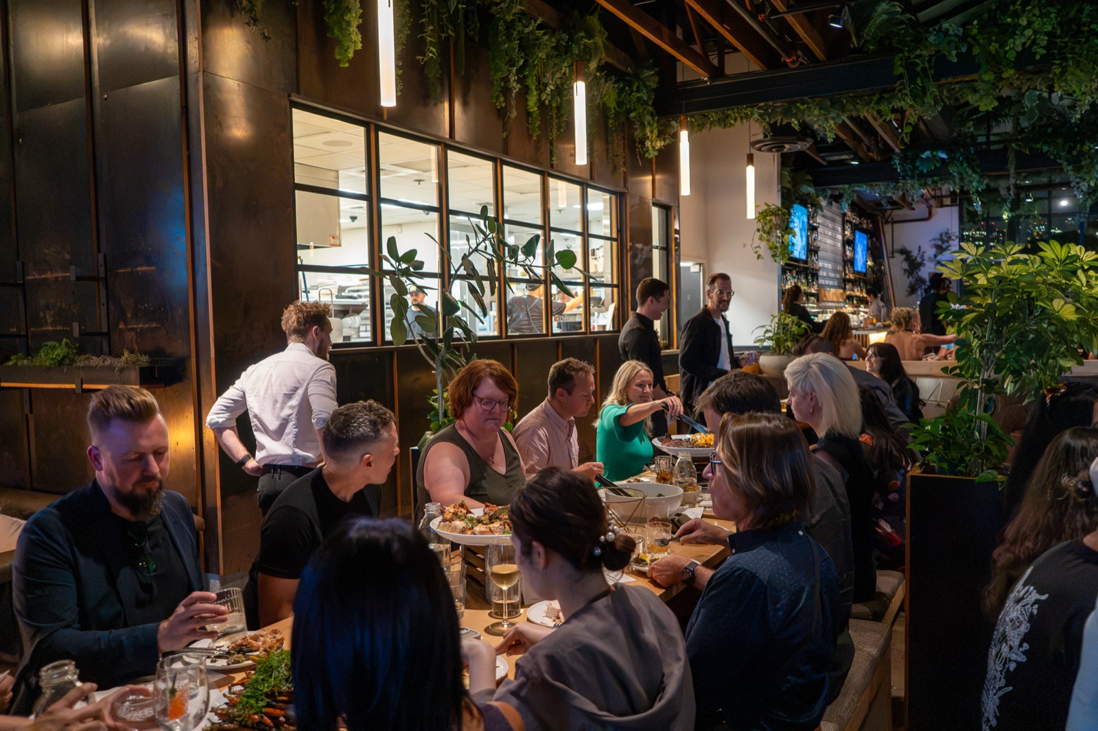 Wide view of the restaurant with guests at the table and standing groups