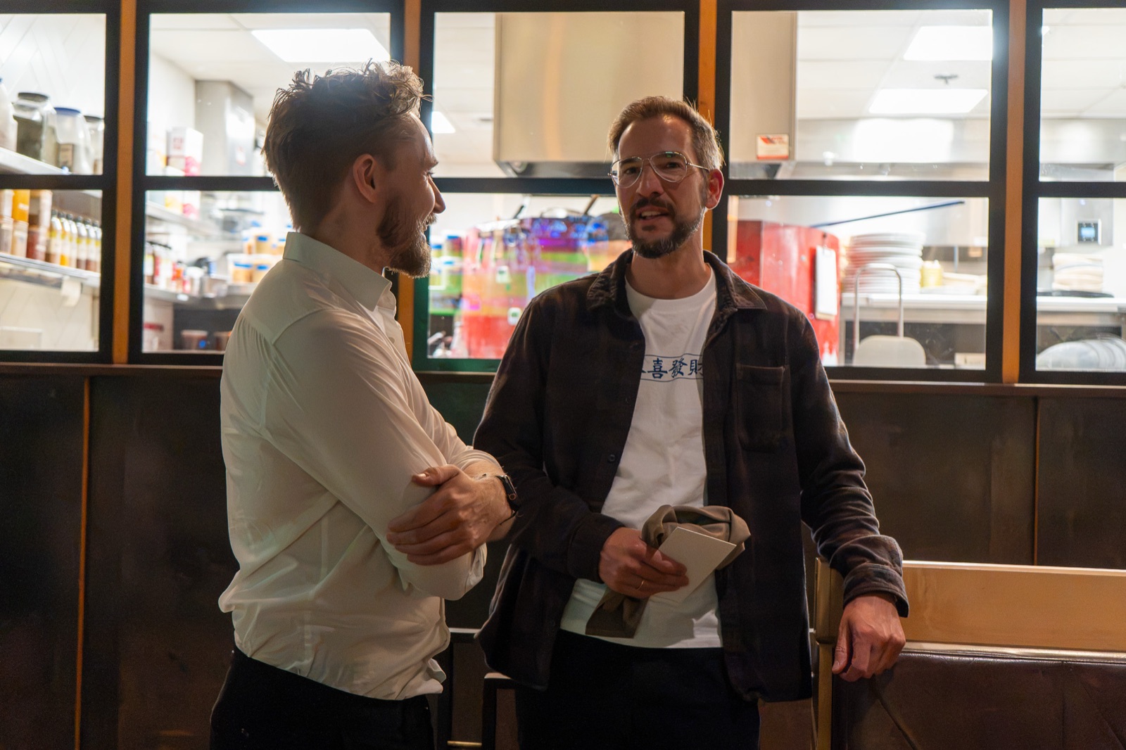 Two guests in conversation standing by the open kitchen